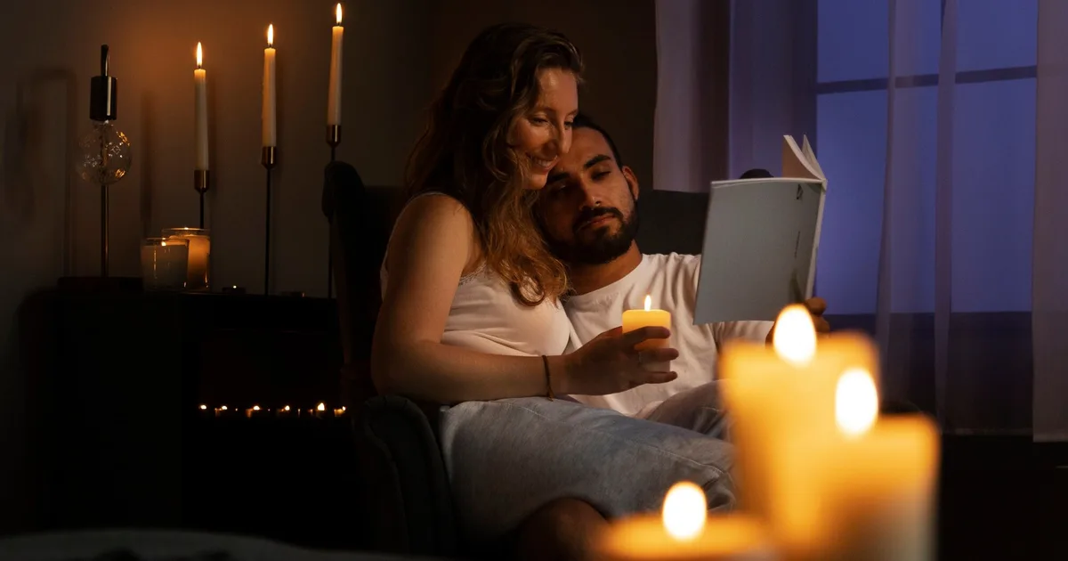 Casal lendo junto à luz de velas durante um apagão em casa — preparação apagão Portugal