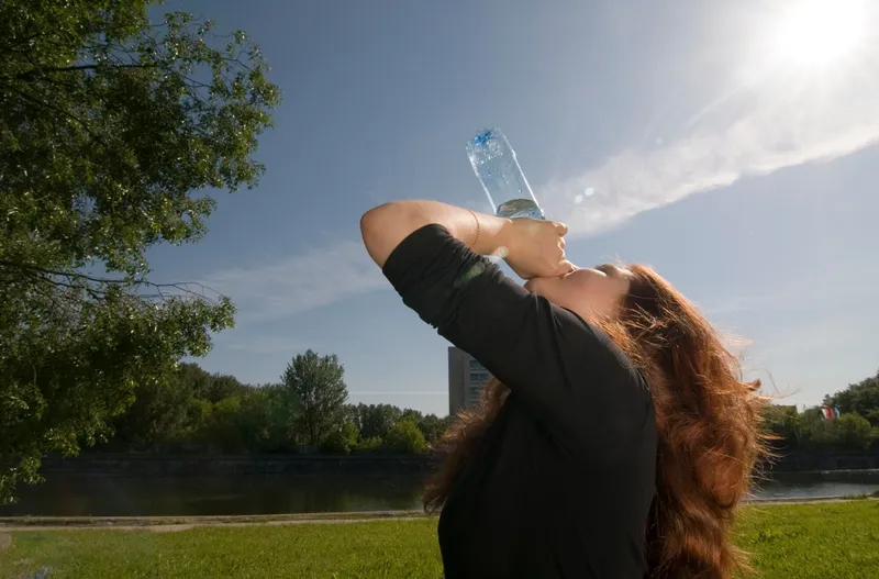 Persona hidratándose en un día de calor extremo con botella de agua